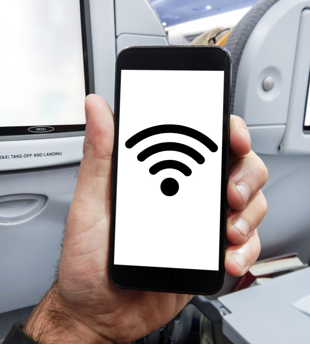 Tanie linie wprowadzają WiFi na pokładzie Foto: ręka trzymająca telefon komórkowy w samolocie