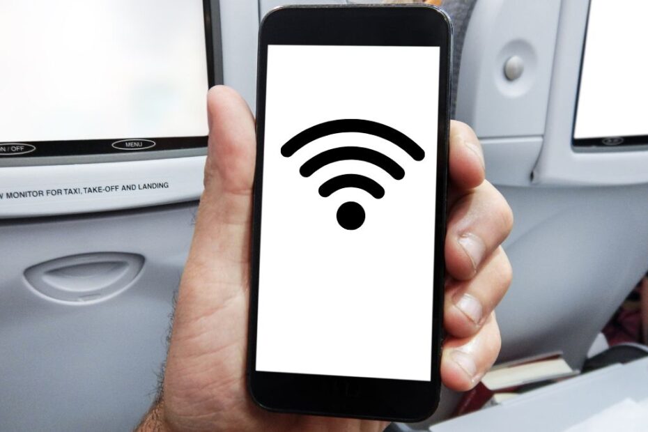 Tanie linie wprowadzają WiFi na pokładzie Foto: ręka trzymająca telefon komórkowy w samolocie